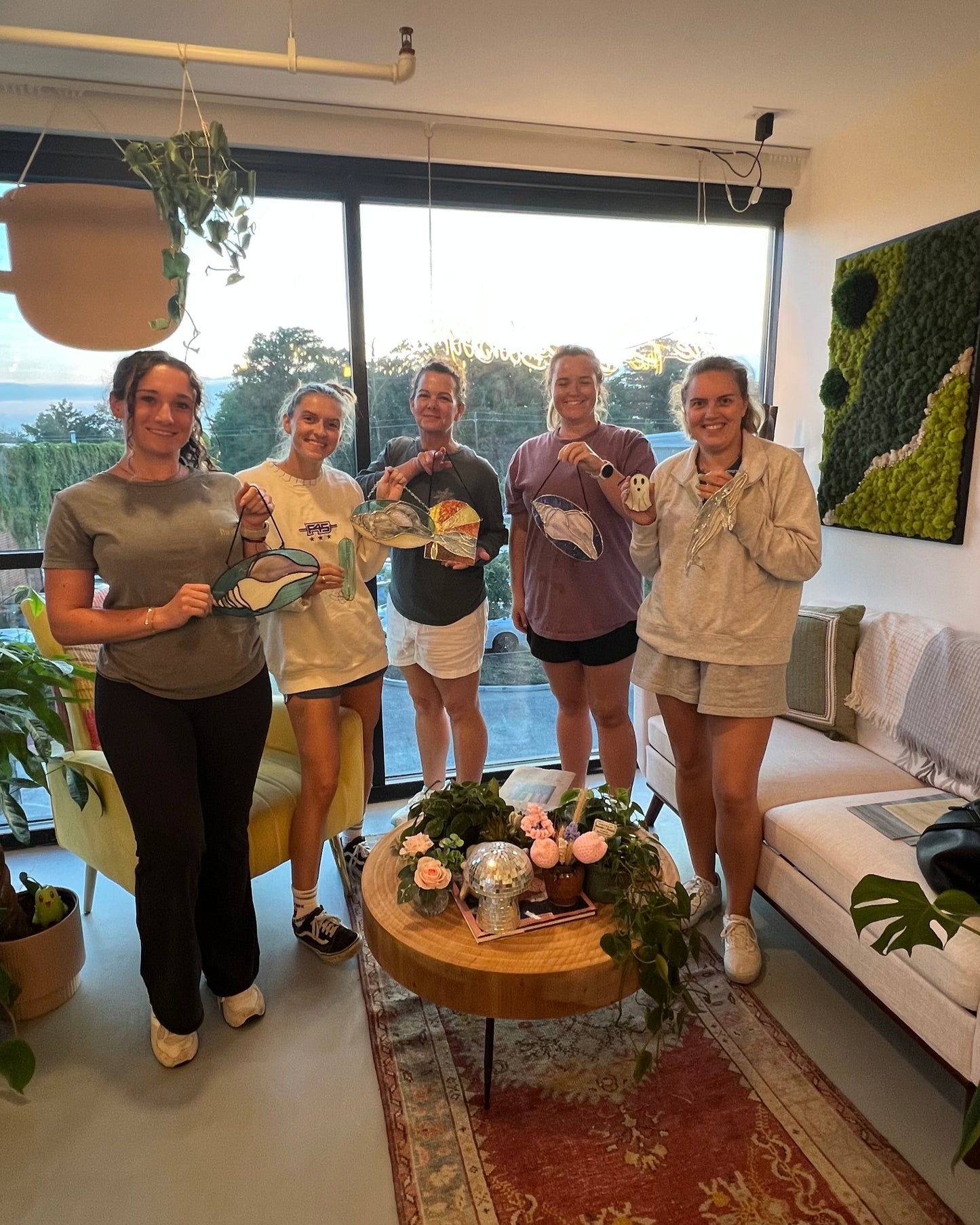 students of a stained glass art class holding up their finished pieces